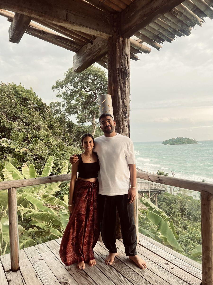 Neshi and partner on a wooden deck overlooking the ocean